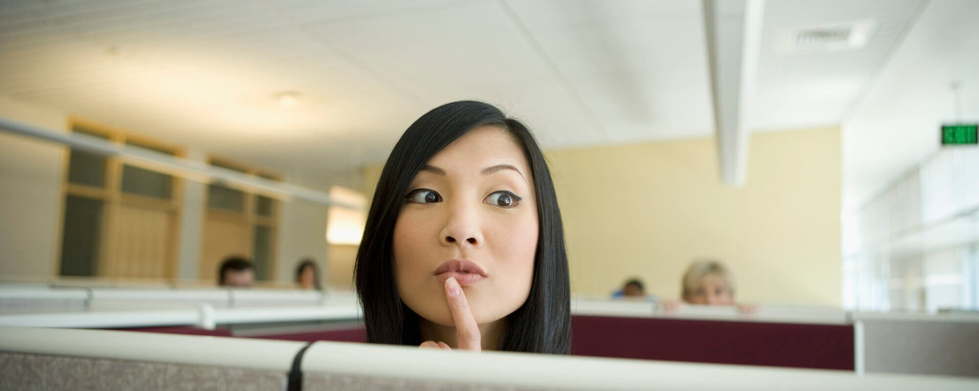 Businesswoman Looking over Cubicle Wall